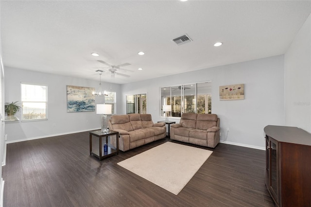 living room featuring ceiling fan with notable chandelier and dark wood-type flooring