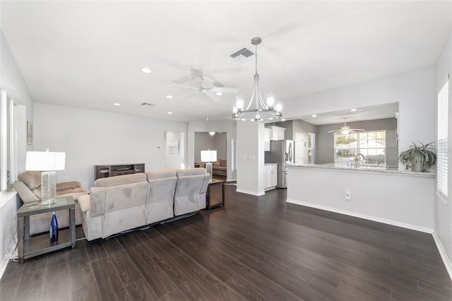 living room featuring dark wood-type flooring and ceiling fan with notable chandelier