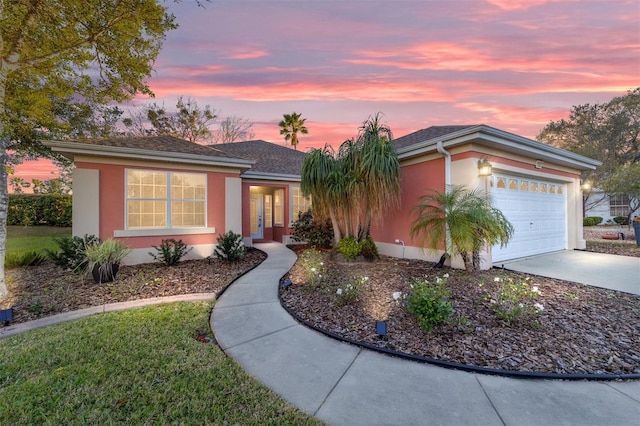 ranch-style house featuring driveway, an attached garage, and stucco siding