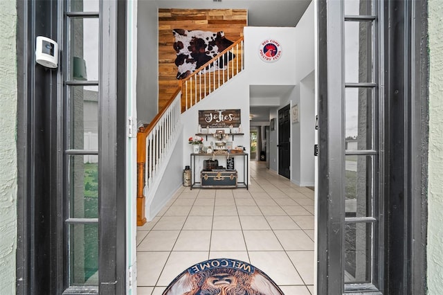 entrance foyer with baseboards, light tile patterned flooring, stairway, and a towering ceiling