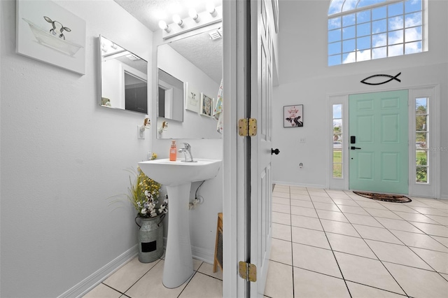 bathroom featuring tile patterned flooring, a textured ceiling, baseboards, and a wealth of natural light