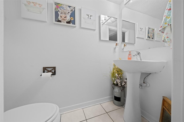 bathroom featuring toilet, tile patterned flooring, baseboards, and a textured ceiling