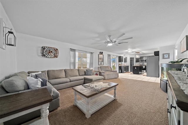 living room with a textured ceiling, a ceiling fan, and light colored carpet