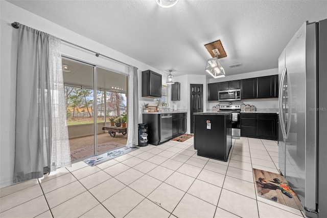 kitchen featuring a kitchen island, visible vents, light countertops, appliances with stainless steel finishes, and dark cabinetry