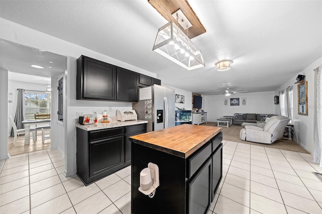 kitchen featuring a kitchen island, open floor plan, dark cabinetry, and stainless steel fridge with ice dispenser