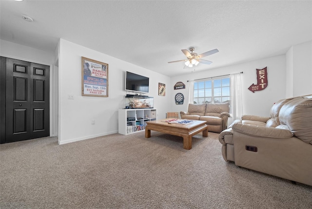 living room featuring a ceiling fan, carpet flooring, a textured ceiling, and baseboards