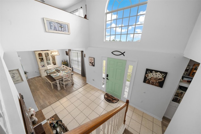 entrance foyer with light wood-type flooring, a high ceiling, and baseboards