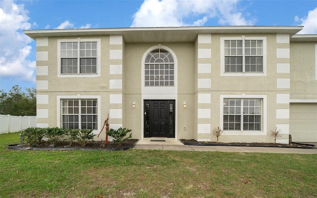 view of front of home featuring a garage, fence, a front lawn, and stucco siding