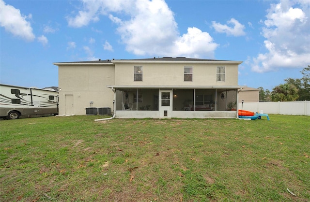 rear view of house with central air condition unit, a sunroom, fence, and a yard