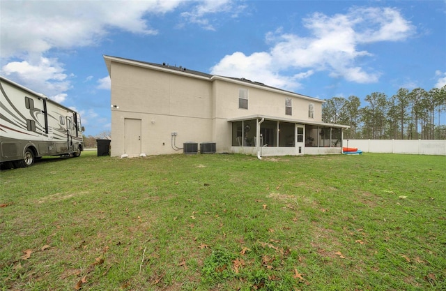 rear view of house featuring cooling unit, a sunroom, a yard, and fence