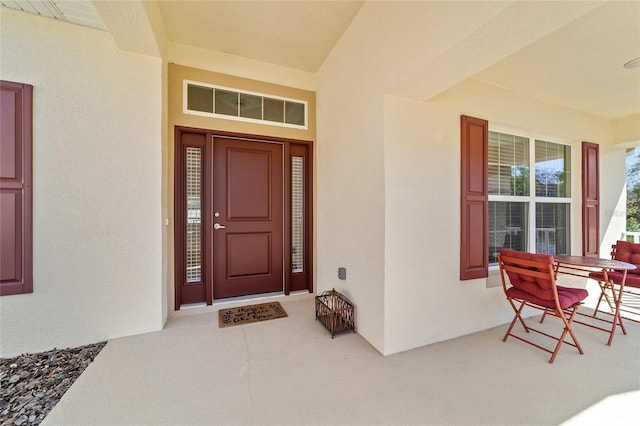 doorway to property with a porch and stucco siding