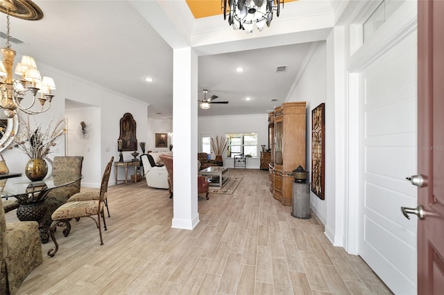 entryway with visible vents, ornamental molding, light wood-type flooring, baseboards, and ceiling fan with notable chandelier