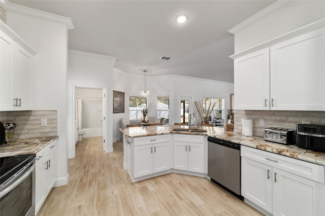 kitchen featuring appliances with stainless steel finishes, a sink, a peninsula, and ornamental molding