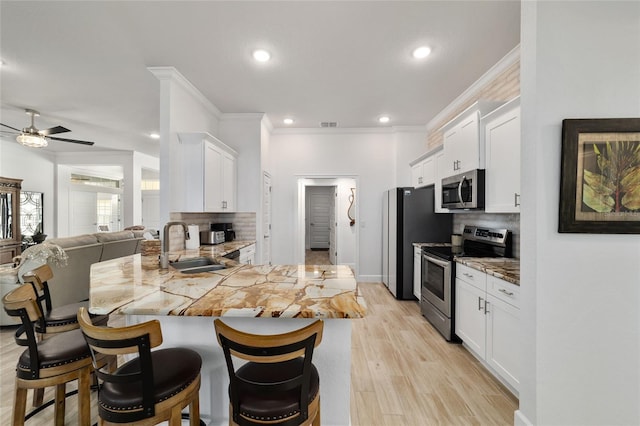 kitchen featuring tasteful backsplash, a breakfast bar, a peninsula, stainless steel appliances, and a sink