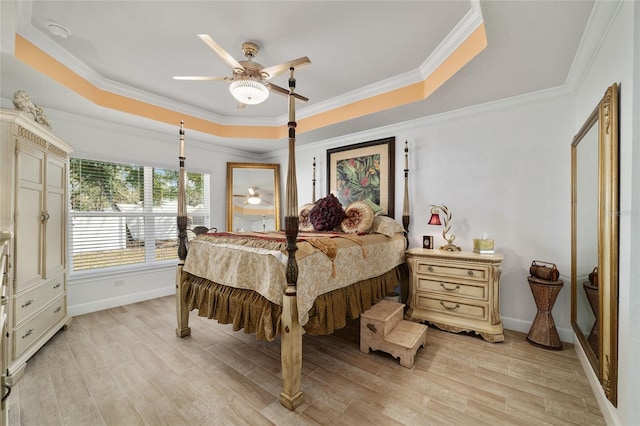 bedroom featuring ornamental molding, a tray ceiling, baseboards, and light wood finished floors