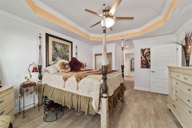 bedroom with a tray ceiling, light wood-type flooring, visible vents, and crown molding