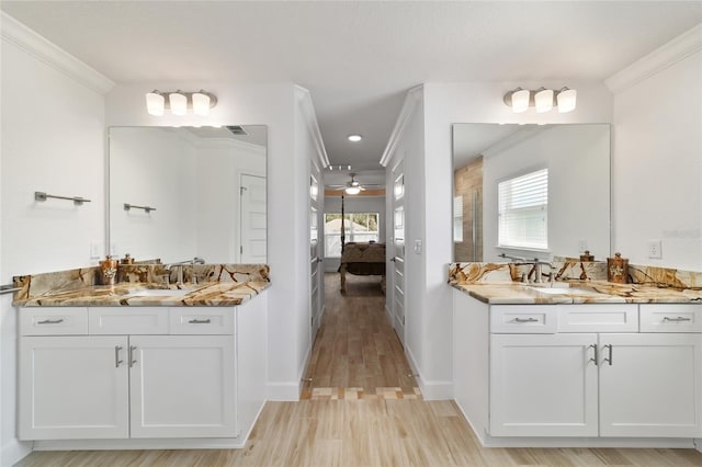 ensuite bathroom featuring a sink, plenty of natural light, ensuite bath, and crown molding