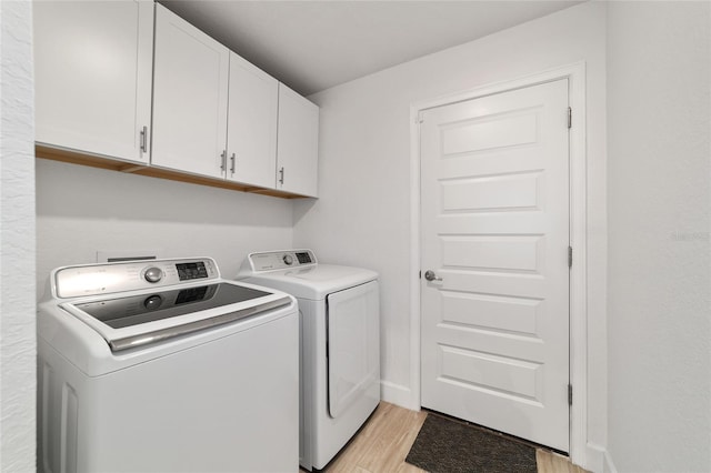 clothes washing area with cabinet space, baseboards, separate washer and dryer, and light wood-style floors