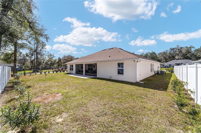 rear view of property with central AC unit, a lawn, a fenced backyard, and stucco siding