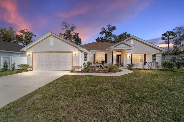 ranch-style home with a garage, concrete driveway, covered porch, a front lawn, and stucco siding