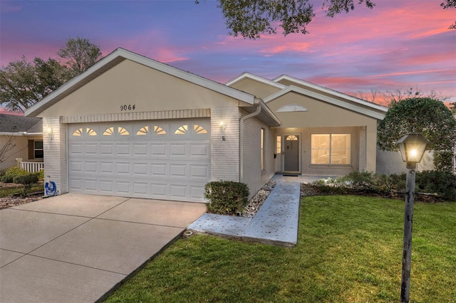 ranch-style home featuring a garage, concrete driveway, brick siding, and a yard