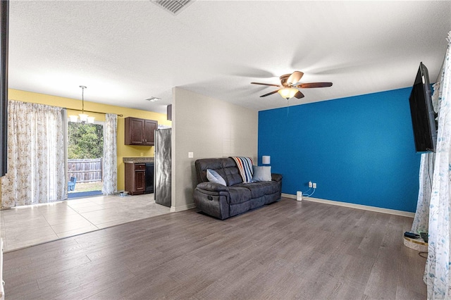 sitting room featuring hardwood / wood-style floors, ceiling fan with notable chandelier, and a textured ceiling