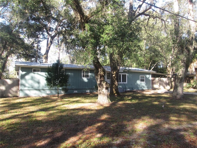 back of property with crawl space, fence, and a yard