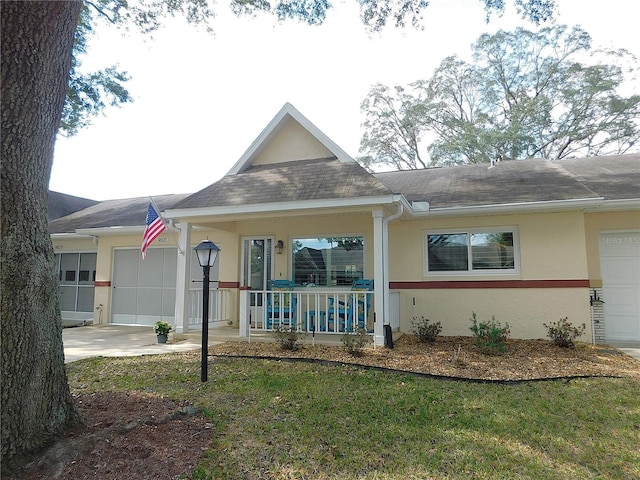 view of front of home featuring covered porch, a front lawn, and a garage