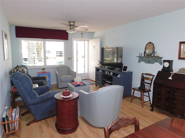 living room with light hardwood / wood-style floors, ceiling fan, and a textured ceiling