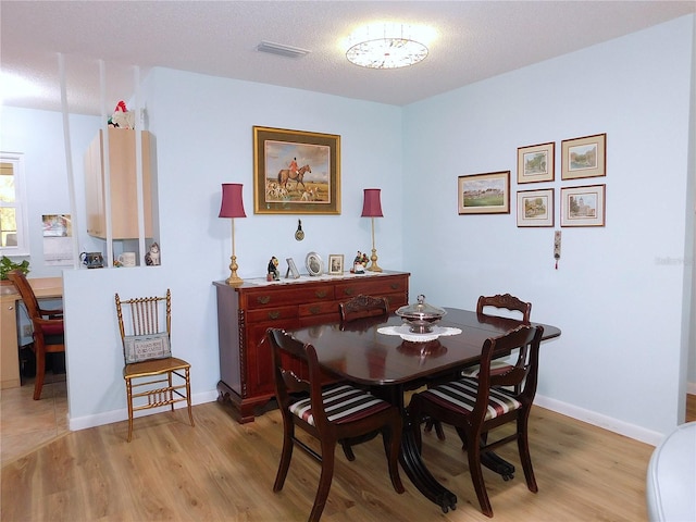 dining space with light hardwood / wood-style flooring and a textured ceiling