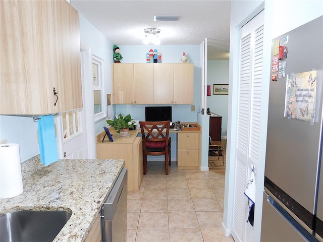 kitchen featuring light tile patterned flooring, appliances with stainless steel finishes, light stone countertops, and light brown cabinetry