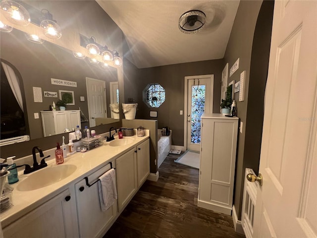 bathroom with double vanity, vaulted ceiling, a sink, and wood finished floors