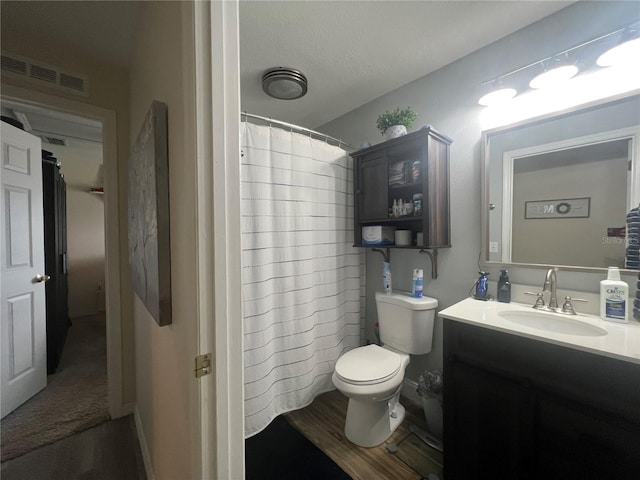 bathroom featuring visible vents, toilet, a textured ceiling, vanity, and wood finished floors