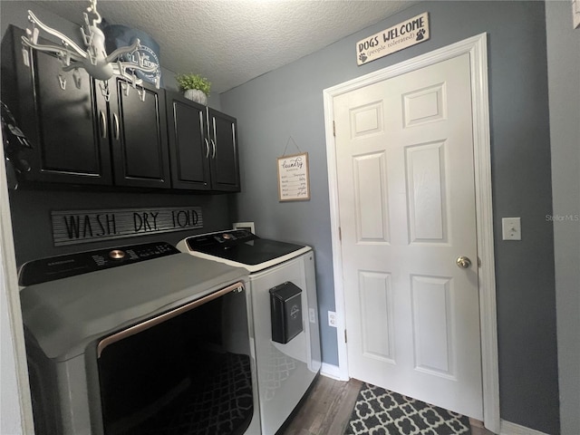 laundry room with cabinet space, dark wood-type flooring, washer and clothes dryer, and a textured ceiling