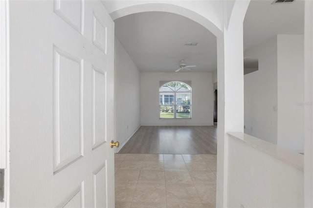 entrance foyer featuring ceiling fan, visible vents, arched walkways, and light tile patterned flooring