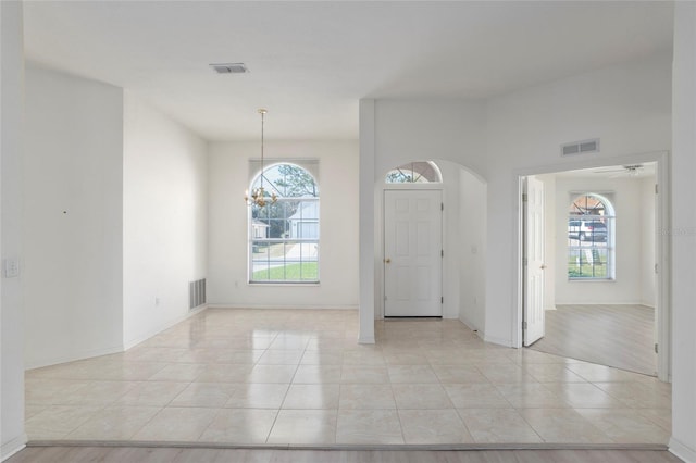 entryway with arched walkways, visible vents, and light tile patterned floors