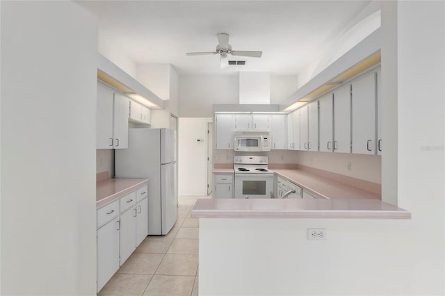 kitchen with light countertops, white appliances, a peninsula, and white cabinetry