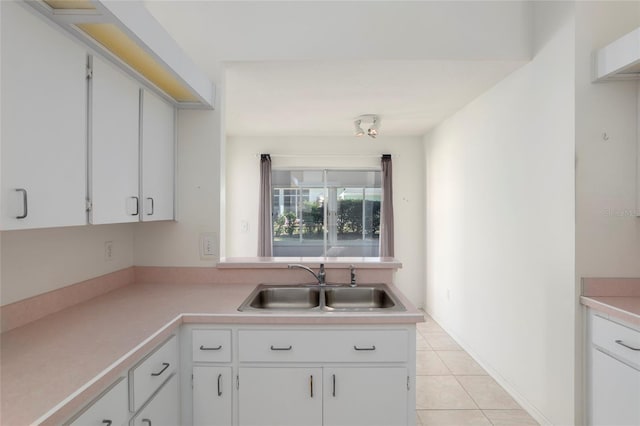 kitchen with white cabinets, light countertops, a sink, and light tile patterned flooring