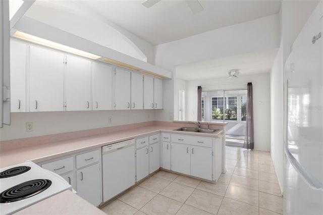 kitchen with white appliances, white cabinets, a peninsula, light countertops, and a sink