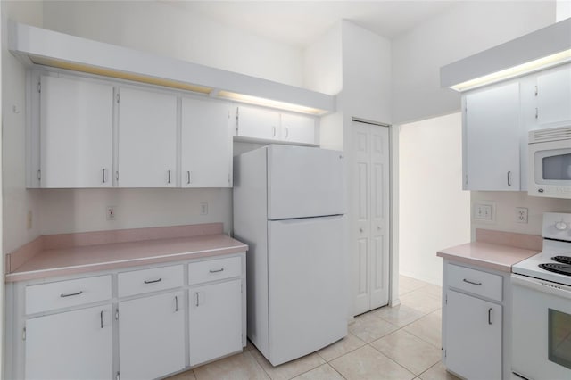 kitchen with light tile patterned floors, light countertops, white appliances, and white cabinets