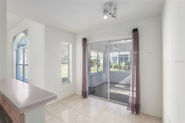 doorway to outside with light tile patterned floors, plenty of natural light, and baseboards