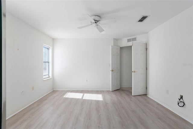 spare room featuring light wood finished floors, ceiling fan, visible vents, and baseboards