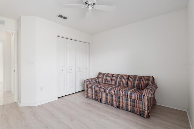 living area featuring light wood-type flooring, visible vents, ceiling fan, and baseboards