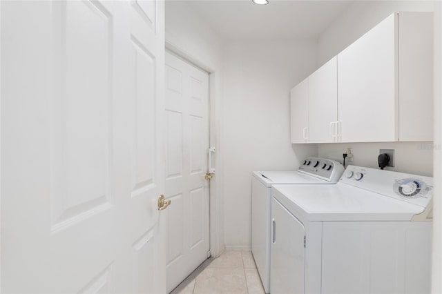 clothes washing area with washer and dryer, cabinet space, and light tile patterned flooring