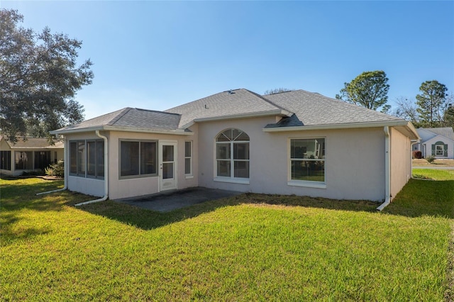 rear view of property with roof with shingles, a lawn, a patio, and stucco siding