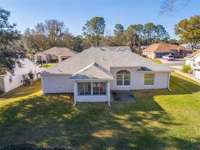 rear view of house featuring roof with shingles, a residential view, and a yard