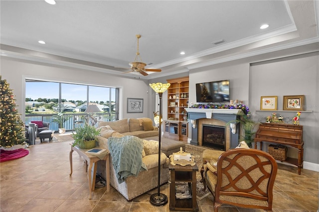 living room featuring ceiling fan, crown molding, and a raised ceiling