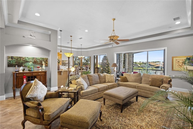 living room with a tray ceiling, ceiling fan, and crown molding