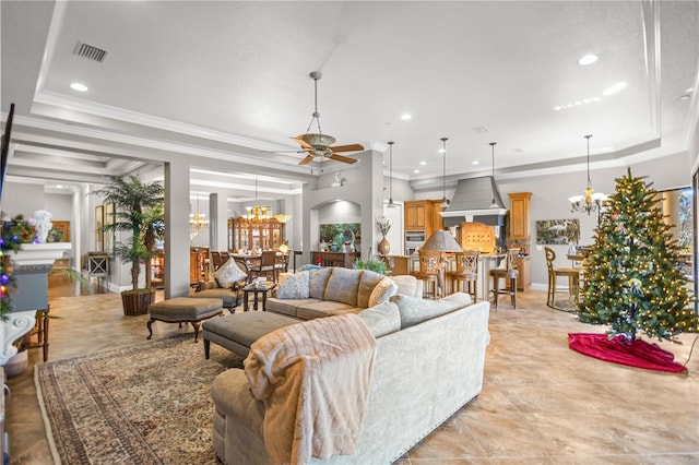 living room featuring a tray ceiling, ornamental molding, and ceiling fan with notable chandelier