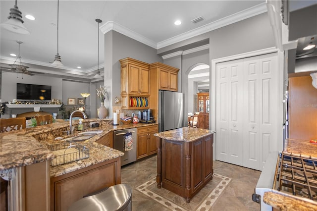 kitchen featuring appliances with stainless steel finishes, sink, a center island, ceiling fan, and light stone countertops